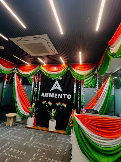 A reception desk fully decorated in a tricolor theme for Republic Day, featuring a branded backdrop and fabric drapes.