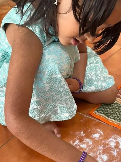 A child practices writing in a tray of powder. This sensorial approach to writing is a fun, pressure-free way to develop the motor skills needed for holding a pencil.