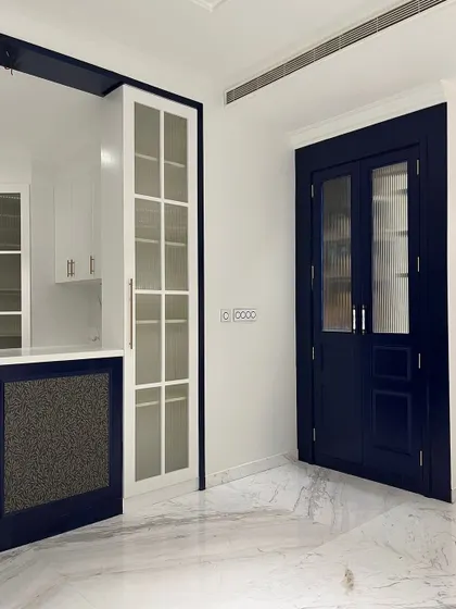 A study in contrast. We used a deep navy blue for the doors and bar area against crisp white walls and marble floors. The result is a chic, sophisticated space that feels both bold and timeless.