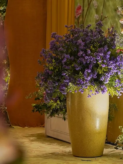 A single vase of purple flowers, with the soft, warm glow of the event in the background.