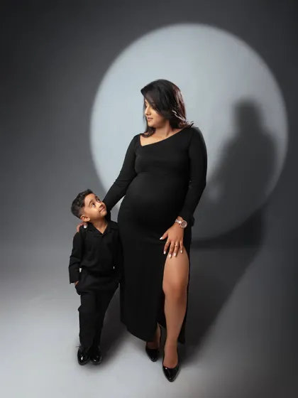 A powerful studio maternity portrait of a mother and her son. The dramatic spotlight on a simple grey background creates a classic and artistic image.