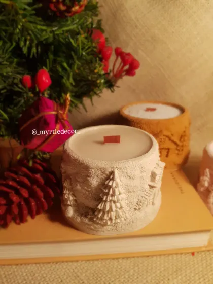 Our white Winter Lights Jar Candle styled on a book with festive greenery. It’s a perfect little piece to create a cozy reading nook during the holidays.