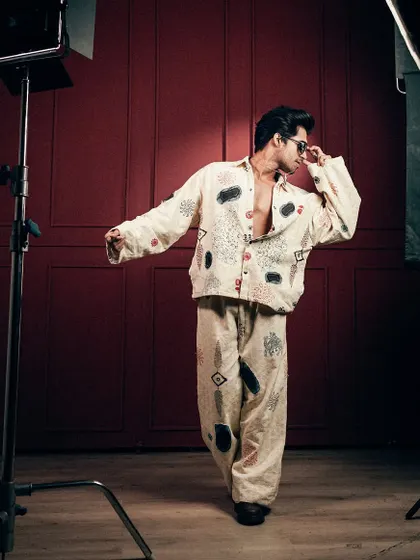 A behind-the-scenes style shot from a men's fashion editorial, showing the lighting setup and a raw, in-motion pose.