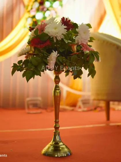 This elegant floral arrangement on a tall, golden stand adds a touch of sophistication to the stage area or as a floor accent. The mix of white and red flowers provides a classic color combination suitable for any celebration.