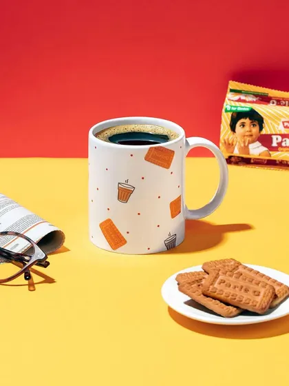 A lifestyle scene featuring the Parle-G mug. I created a classic "chai and biscuit" moment with a newspaper and glasses to evoke a sense of nostalgia and everyday comfort.