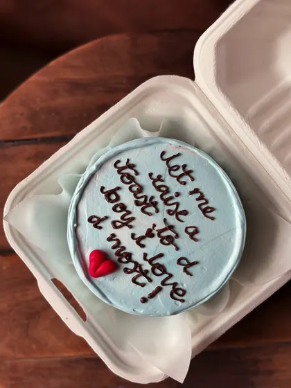 A sweet and romantic message on a cake: "let me raise a toast to a boy i love d most!" This light blue bento cake with a single red heart is a perfect personal gift.