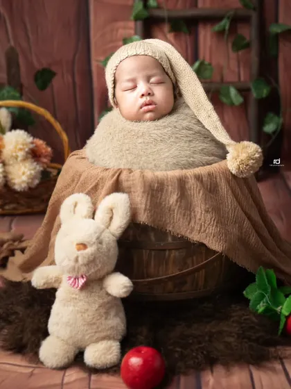 A sleepy little gnome in a bucket. The earthy tones, pom-pom hat, and stuffed bunny create a whimsical forest scene.