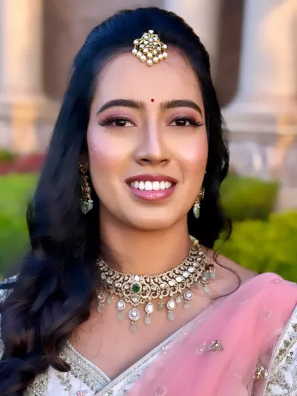 Keerthi's reception makeup showcases a beautiful, dewy highlight on the cheeks that catches the light and gives a youthful glow.