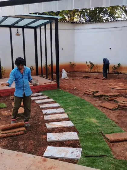 Here is my team in the middle of a garden installation. We are laying down rolls of natural grass sod and setting a stone pathway, with a new pergola structure already in place.