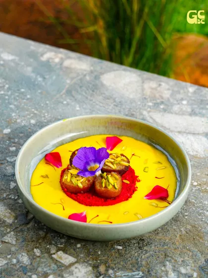 A dessert that's almost too pretty to eat. This vibrant dish is garnished with edible flowers and pistachios, a treat for the eyes and the palate.
