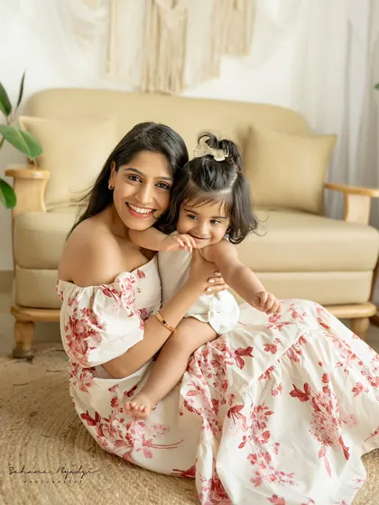 A mother and daughter share a sweet moment. The daughter's smile as she sits in her mother's lap is simply precious.