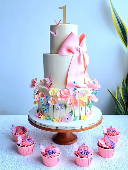 The floral first birthday cake with matching pink and purple cupcakes.