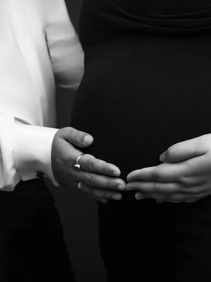 A different perspective on connection. This detail shot shows the couple's hands gently placed on the bump, a simple yet profound image of their partnership.