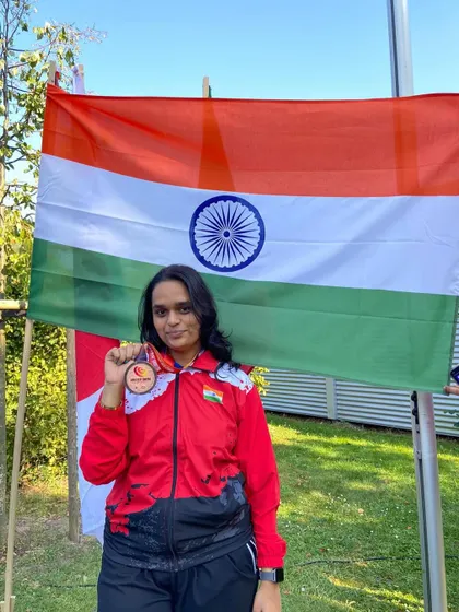 Natasha Joshi, a member of our club, holding the Indian flag after winning a bronze medal at the World Deaf Shooting Championships in Germany.