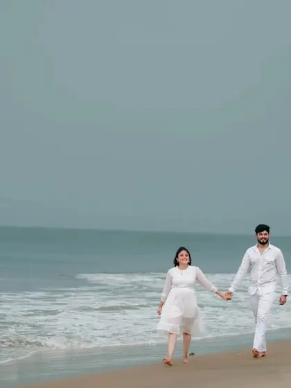 A wide, scenic shot of a couple on the beach, perfect for capturing the beauty of the location and the couple's connection within it.