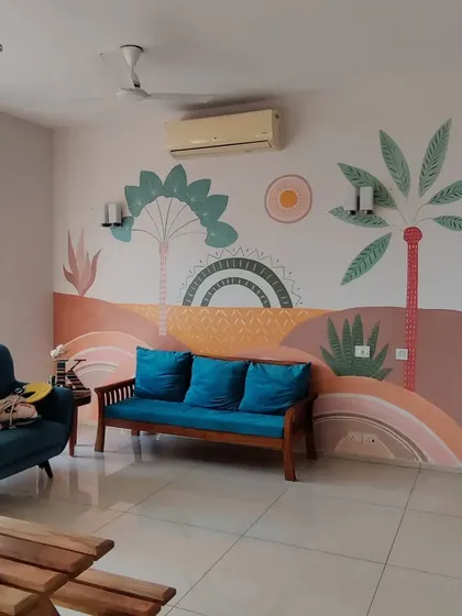 A finished living room featuring a custom Boho-style mural. The design uses a warm, earthy pastel palette with abstract landscape elements and tropical plants to create a relaxed and sunny vibe.