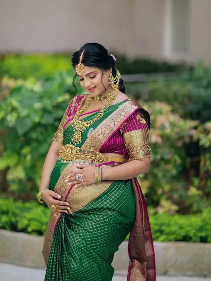 A full-length shot of the mom-to-be, showcasing how the traditional jewellery and silk saree come together to create a timeless and elegant maternity look.