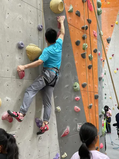 A group of friends watches and supports a climber on the wall. Climbing is always more fun when you share the experience.