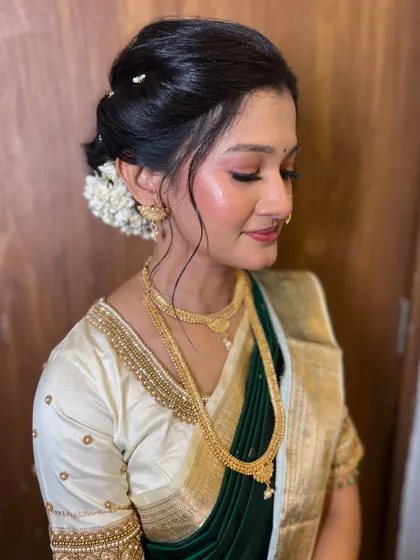 A soft and dreamy engagement look. The makeup features glowing skin and soft pink tones, paired with a classic floral bun for a touch of traditional elegance.