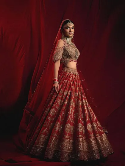 A full-length shot of a traditional red lehenga. I teach not just makeup, but also how to consider the entire silhouette, from the outfit to the jewelry, to create a complete and harmonious bridal vision.