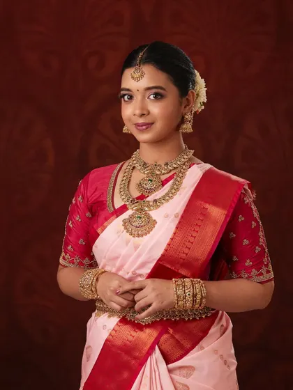 This model looks graceful in a classic temple jewellery set against a pink and red saree.