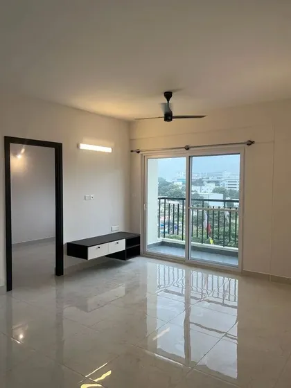 A minimalist living room with a simple floating TV console, showcasing a clean and uncluttered approach to design. The large sliding door provides ample natural light and a view of the balcony.