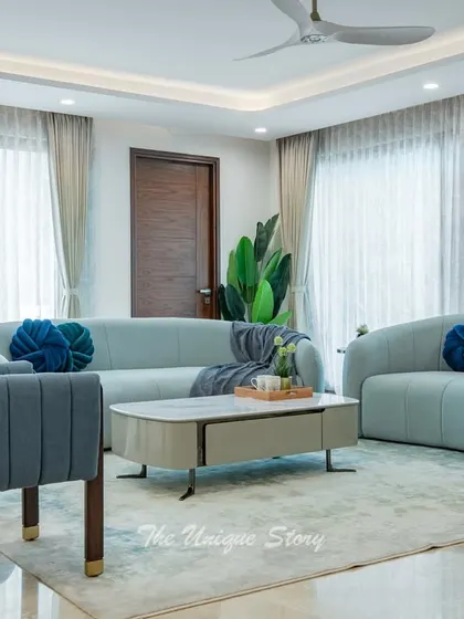 The living area is defined by its comfortable, curved pastel blue sofas and matching ottomans. The soft textures and rounded forms create a gentle and inviting atmosphere, perfect for relaxation and conversation.