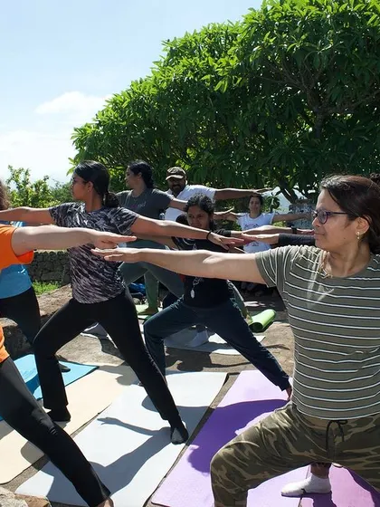 Students practicing Virabhadrasana II (Warrior II) together on a mountaintop, their strength mirroring the landscape.