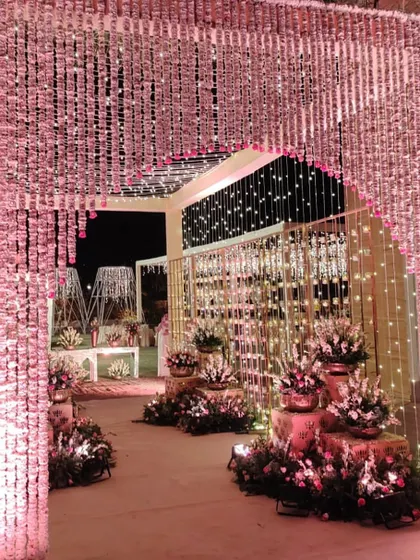 An entrance for a wedding reception in Udaipur, adorned with curtains of fresh traditional Indian flowers and fairy lights.