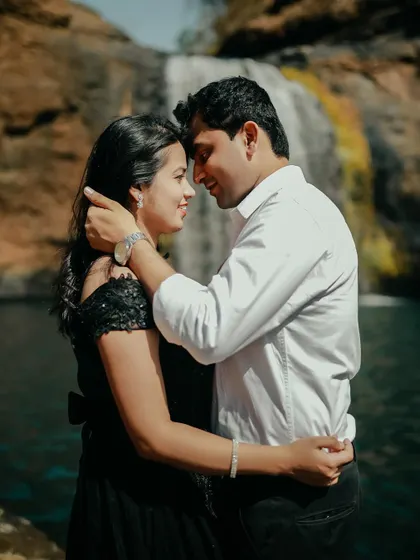 A tender moment captured in time. The groom gently holds her face as they share a loving look, with the waterfall creating a stunning background.