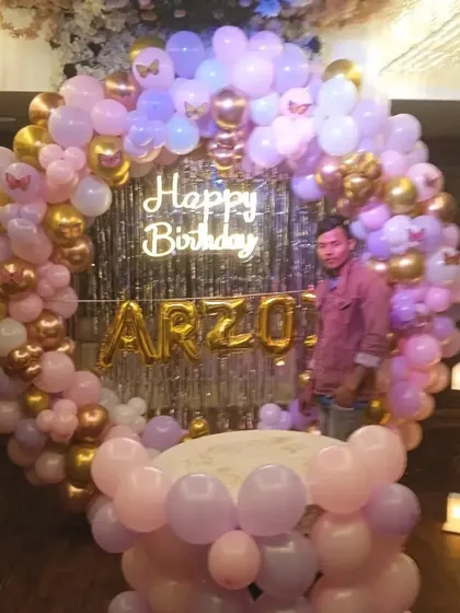 A circular balloon backdrop for Arzo's first birthday. I used a mix of pastel pink, purple, and gold balloons, with a "Happy Birthday" neon sign and a light-up number '1'.