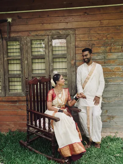 A sweet moment between the bride and groom. Her traditional makeup, with a classic red and white saree, looks beautiful in this rustic, natural setting.