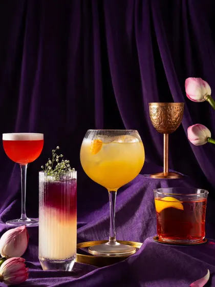 A collection of classic and inventive cocktails from Nara Thai, set against a royal purple backdrop. This styling creates an image of opulence and creativity.