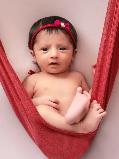This awake shot in the red fabric hammock is so engaging. It's a great example of how we can capture your baby's personality and bright eyes.