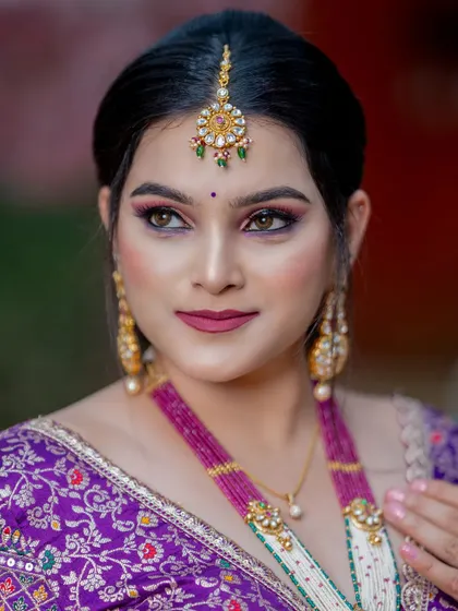 A portrait capturing the elegance of the purple bridal look. The makeup is subtle yet impactful, with a focus on creating a flawless complexion and highlighting her beautiful features.