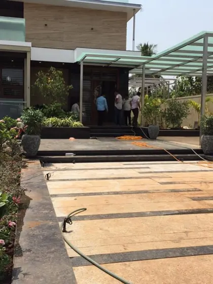 This series of images shows a complete residential project. It features the exterior hardscaping, a rooftop terrace garden with a Plumeria tree, and indoor plants that enhance the grand entrance and living spaces.