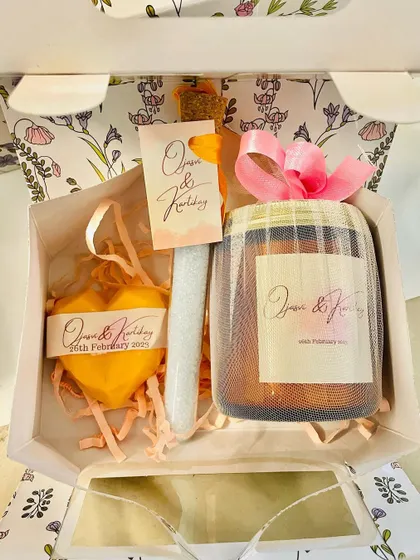 A look inside one of the wedding favor boxes, revealing a personalized candle, a heart-shaped soap, and another scented item.