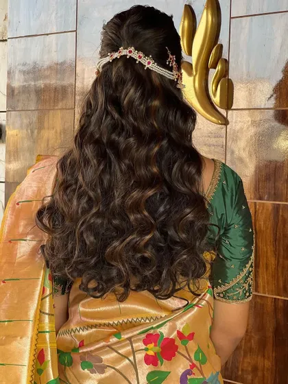 The back view of a modern bridal hairstyle with soft waves and a delicate hair accessory, perfect for a reception or engagement.