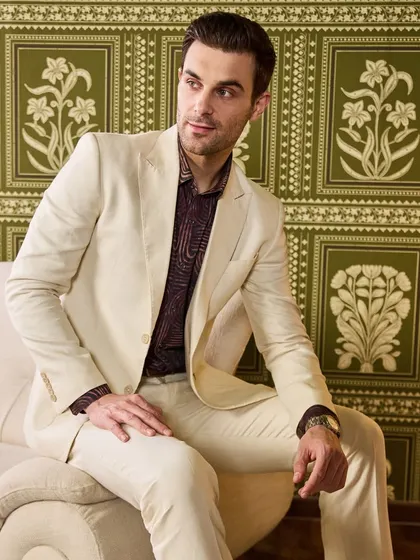 The ivory linen suit offers a clean, sharp silhouette. It's a canvas for your personal style, easily dressed up or down depending on the event.