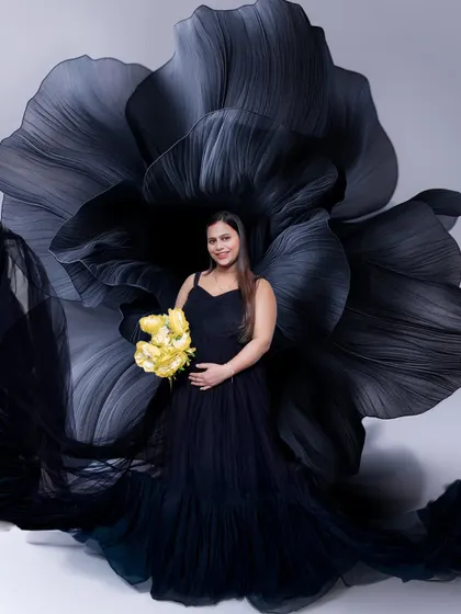 A closer look at this elegant setup. The contrast between the dark, dramatic gown and the bright yellow bouquet creates a stunning focal point in this pregnancy portrait.