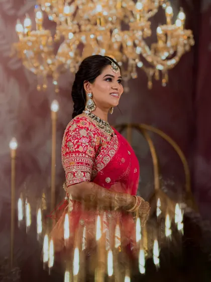 A stunning shot with the chandelier in the background. The bride's makeup is elegant and sophisticated, with a focus on flawless skin and a beautiful smile.
