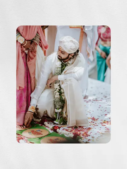 A detail shot of the groom performing a ritual on the ground, surrounded by flower petals.