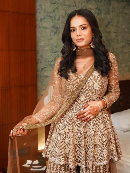 A full-length view showing how this balanced glam look comes together. The bronze tones in the makeup perfectly complement her golden outfit.