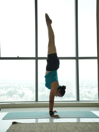 Holding a handstand against a window, playing with balance and enjoying the view from a different perspective.
