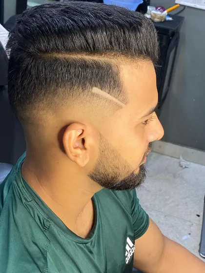 A clean and classic look with a modern twist. This high-fade haircut is accented with a simple, sharp line design and paired with a perfectly shaped beard.