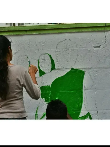 The initial sketch and color blocking phase of a public mural. This collaborative process involves outlining the figures and filling in the base colors before adding the finer details.