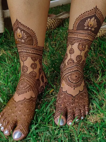 A lovely lotus-themed bridal foot design, looking beautiful on the green grass.