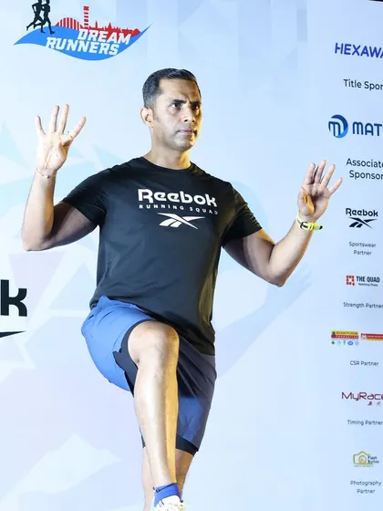 A shot of me demonstrating a balance and stability drill on stage during the warmup for the Chennai marathon.
