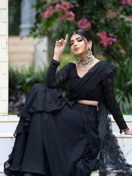 A seated pose in the black outfit, highlighting its elegance and sophistication.