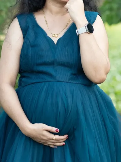 A close-up of the turquoise pleated maternity gown, showing the delicate texture of the bodice. It's a simple, elegant, and comfortable choice.